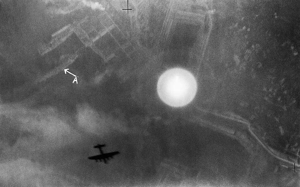 An Avro Lancaster silhouetted over the Italian port of La Spezia on the night of 13-14 April 1943. C3697